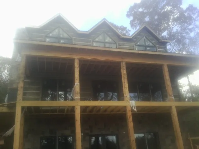Dormers and porch framing on a large log home under construction — Roof Coating work by our crew in North Liberty
