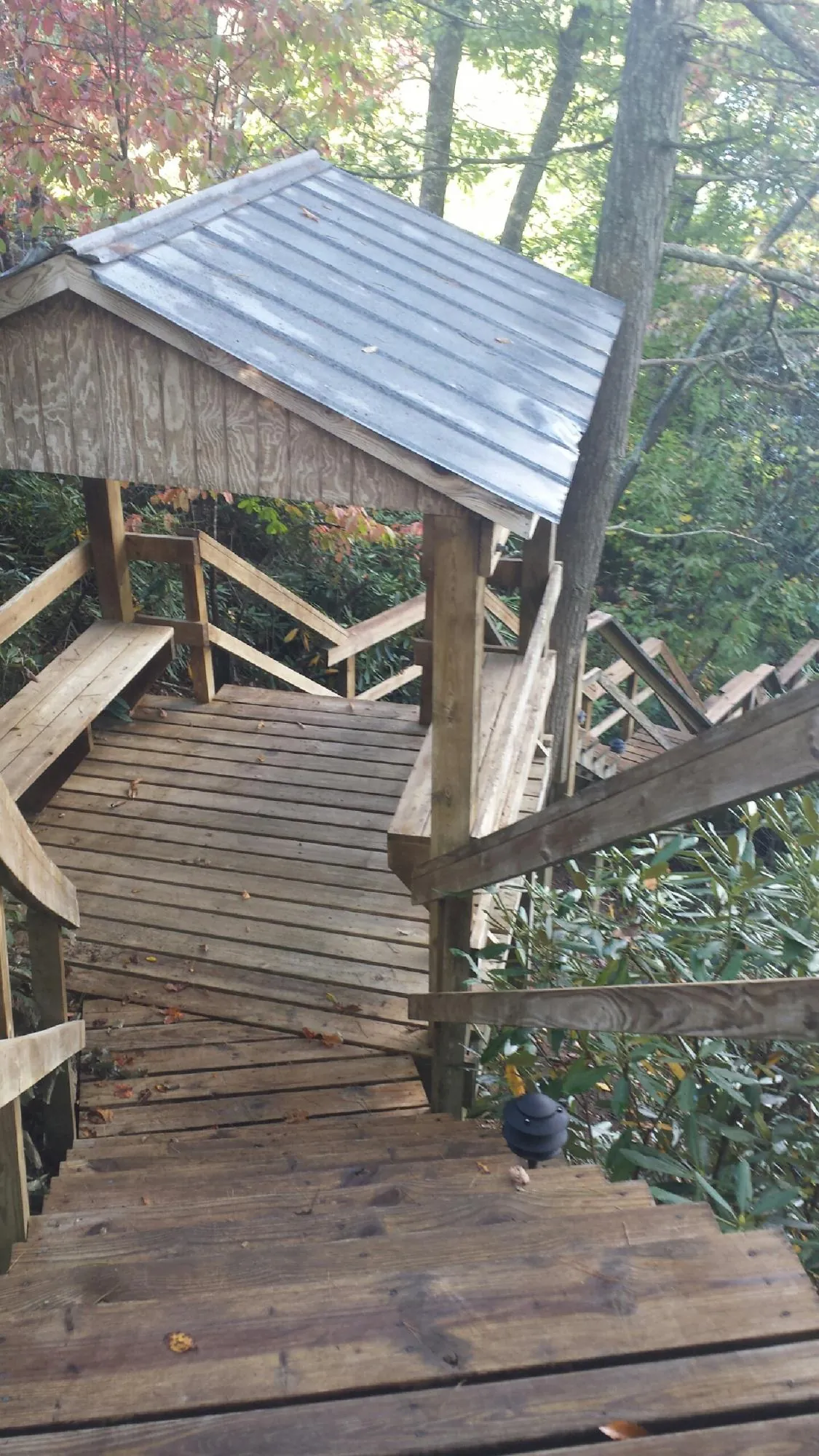Metal roofed shelter over wooden steps on a wooded walkway — Skylight Repair & Installation work by our crew in North Liberty