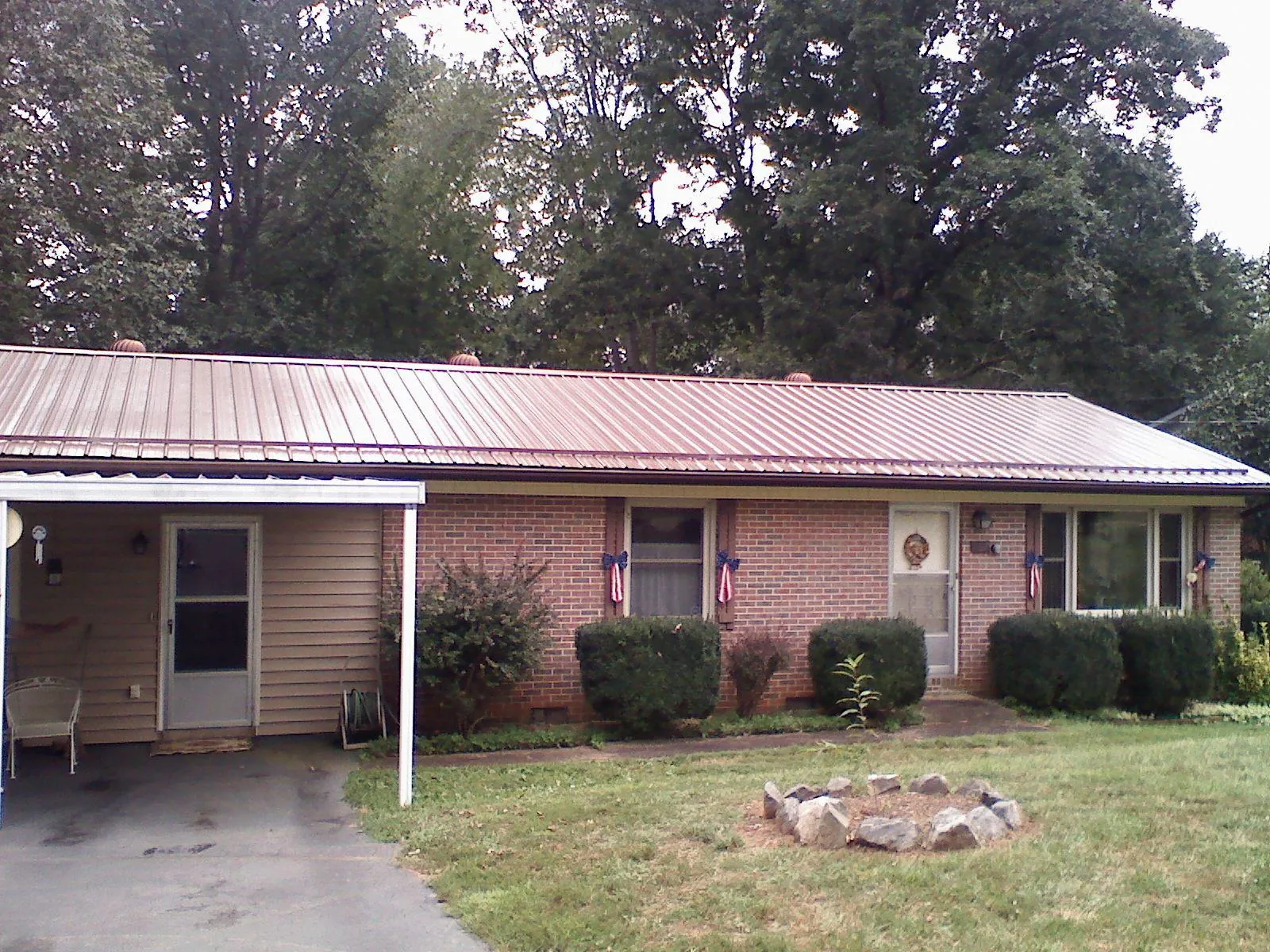 Bronze metal roof and carport on a brick ranch home — Roof Repair work by our crew in North Liberty